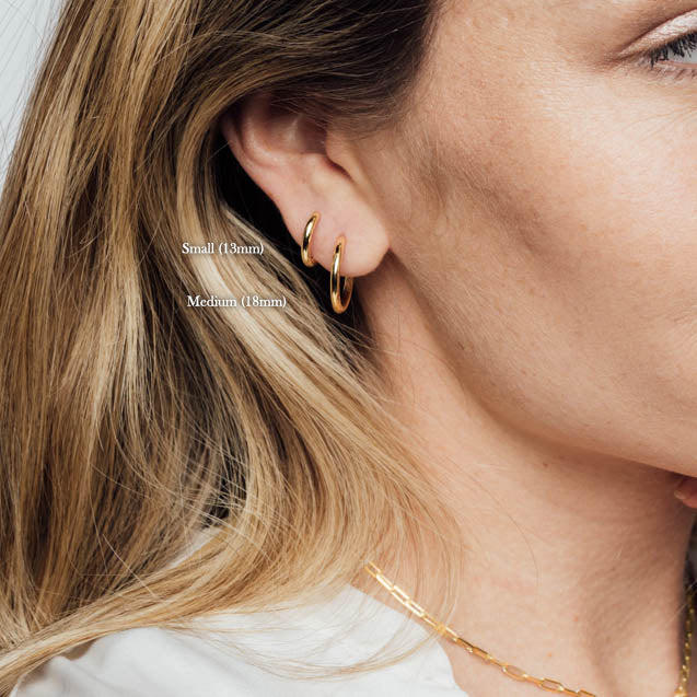 Closeup of Woman wearing 18k gold plated 925 Sterling Silver Small and Medium ‘Classic Hoops’ Earrings with Latch closure on white background