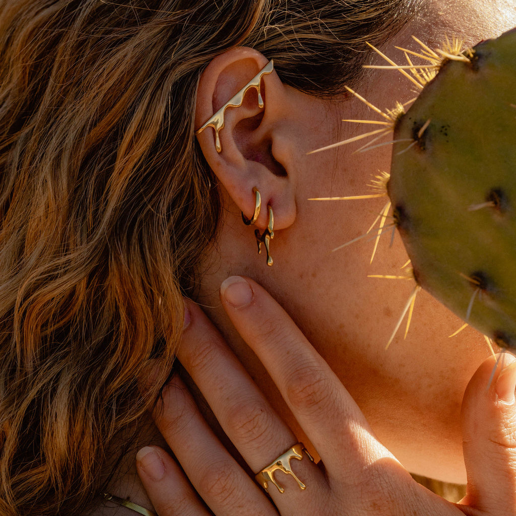 Woman wearing 18k gold plated 925 Sterling Silver ‘Classic Hoops’ and ‘MARIE JUNE Jewelry’ designs behind cactus